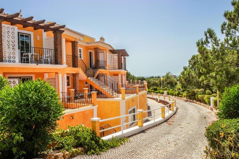 Oranje appartementsgebouwen met balkons langs een kasseiweg tussen het groen bij Colina da Lapa & Villas