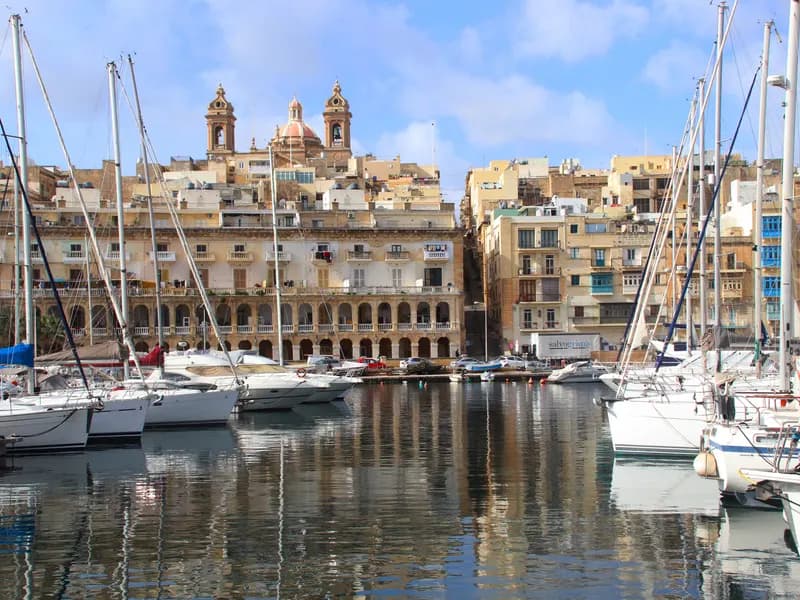 Zeilboten in de jachthaven van Birgu met historische gevels en kerktorens aan de waterkant