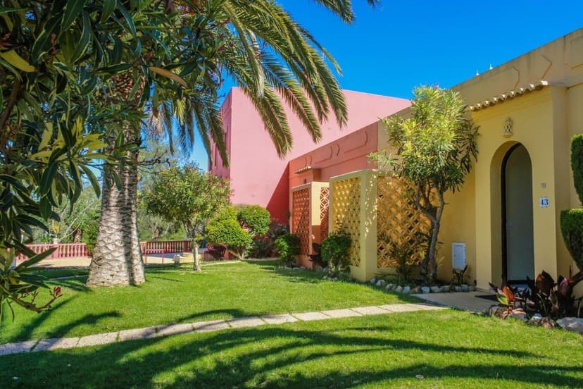Gekleurde lage huisjes met palmbomen en gazon in het aparthotel Colina Village in Carvoeiro