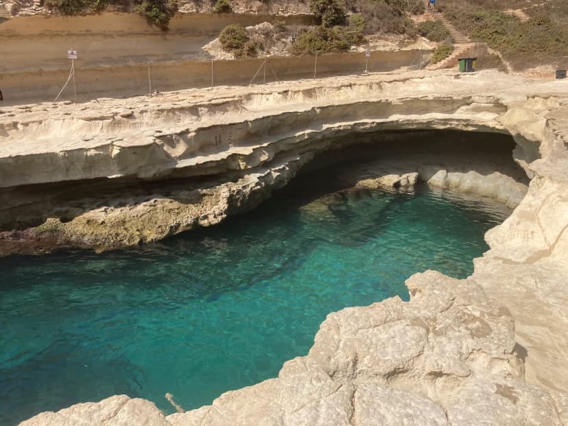 Turkooizen water in de rotsinham van St. Peter's Pool bij Marsaxlokk, omringd door lichte kalksteenrotsen