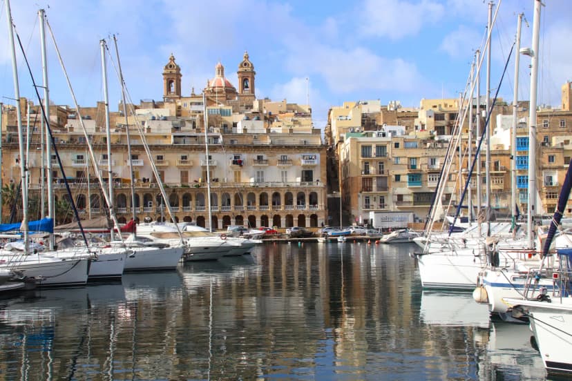 Zeilboten in de jachthaven van Birgu met historische gevels en kerktorens aan de waterkant