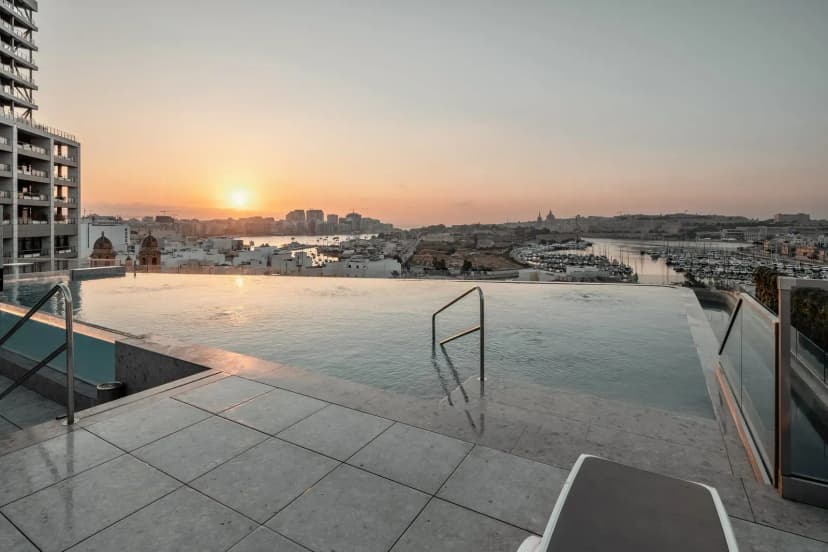 Infinitypool op het dakterras van Grands Suites Hotel Residences & Spa in Gżira, met zicht op de haven van Msida bij zonsondergang