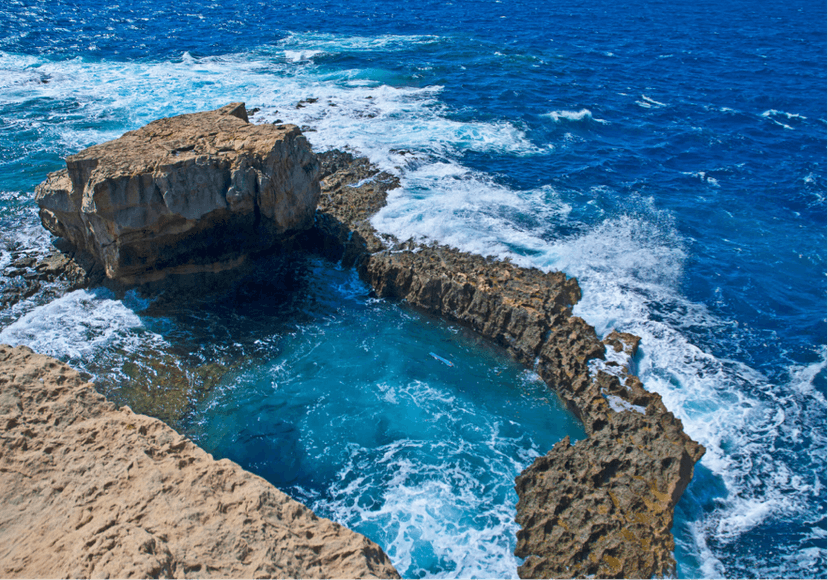 Natuurlijk rotsbad omringd door golven aan de kust van Malta