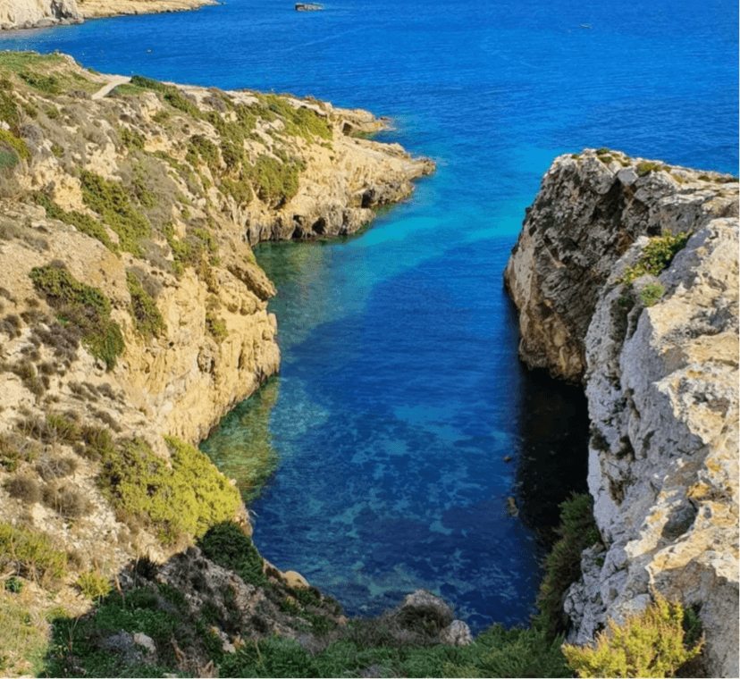 Smalle rotsachtige kreek met diepblauw water in de Maltese archipel