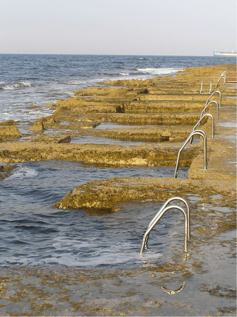 Natuurlijke zwembaden uitgehouwen in de rotsen, met metalen trapjes naar het water