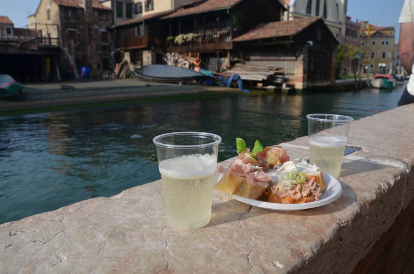 Een glas prosecco met cicchetti, de typische Venetiaanse hapjes, met uitzicht op de lagune